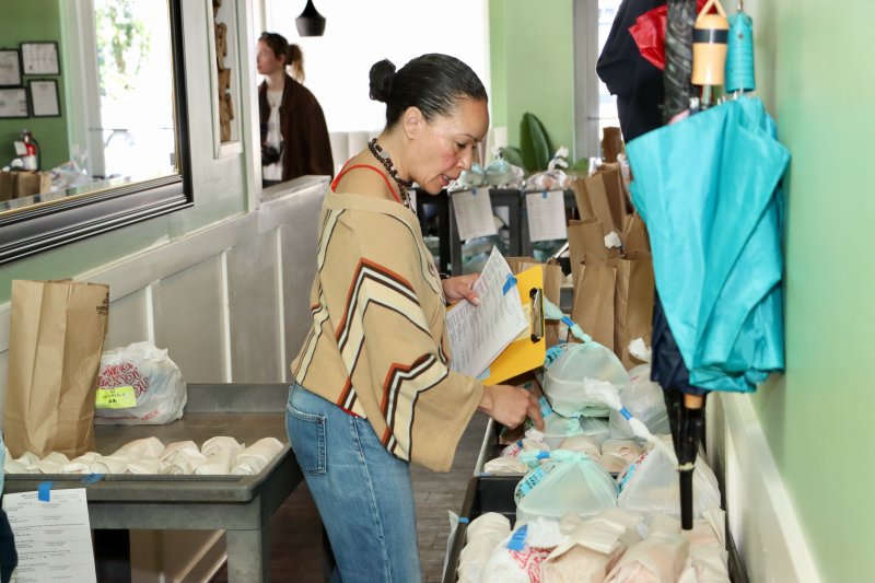Aileen Mateo, co-director and volunteer coordinator, organizes the meals on carts, making it easier for drivers to pull them out to their cars.